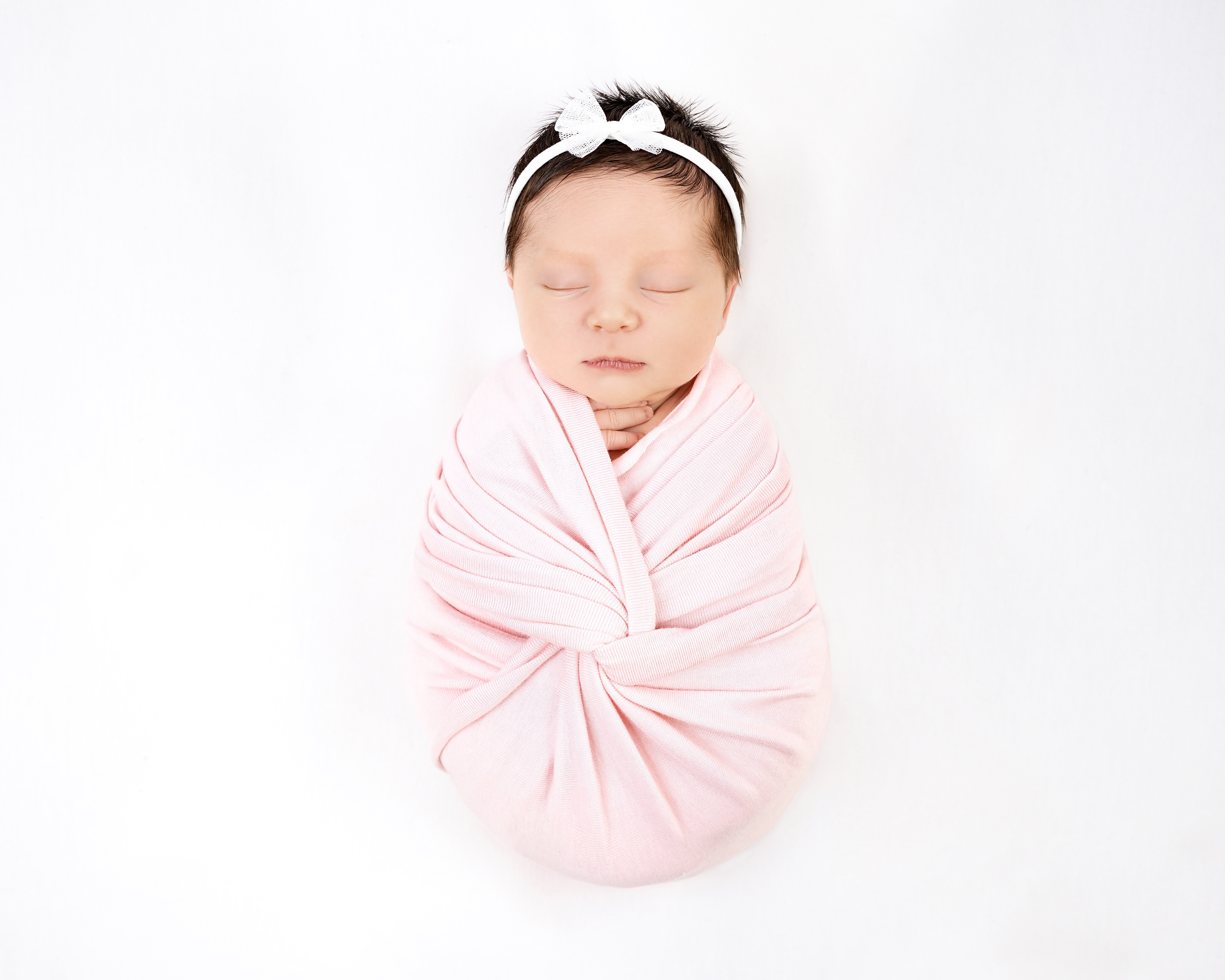 Newborn baby wrapped in a soft pink swaddle